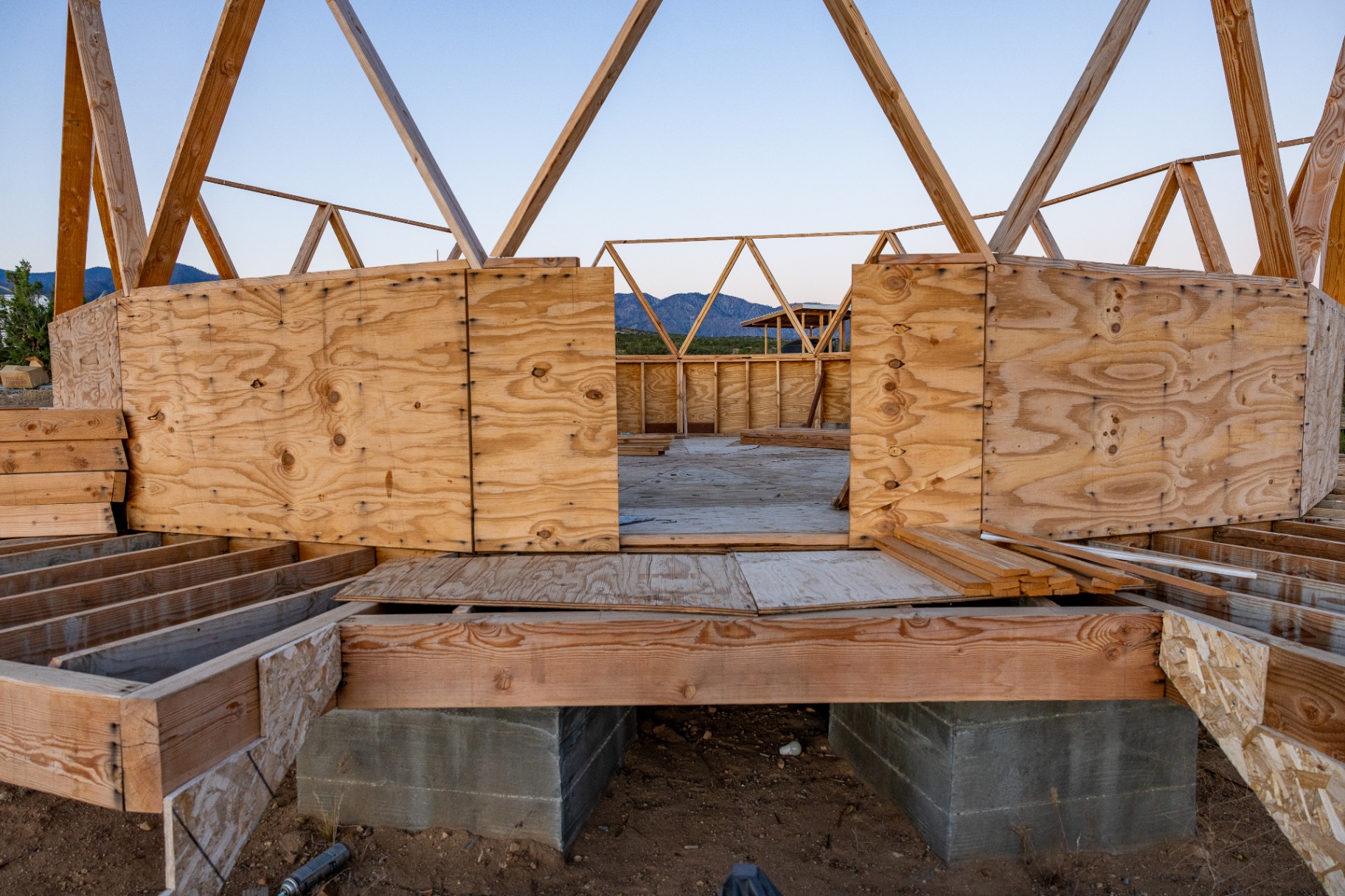 Interior view of the Dome House construction, showing plywood walls and concrete pier foundations