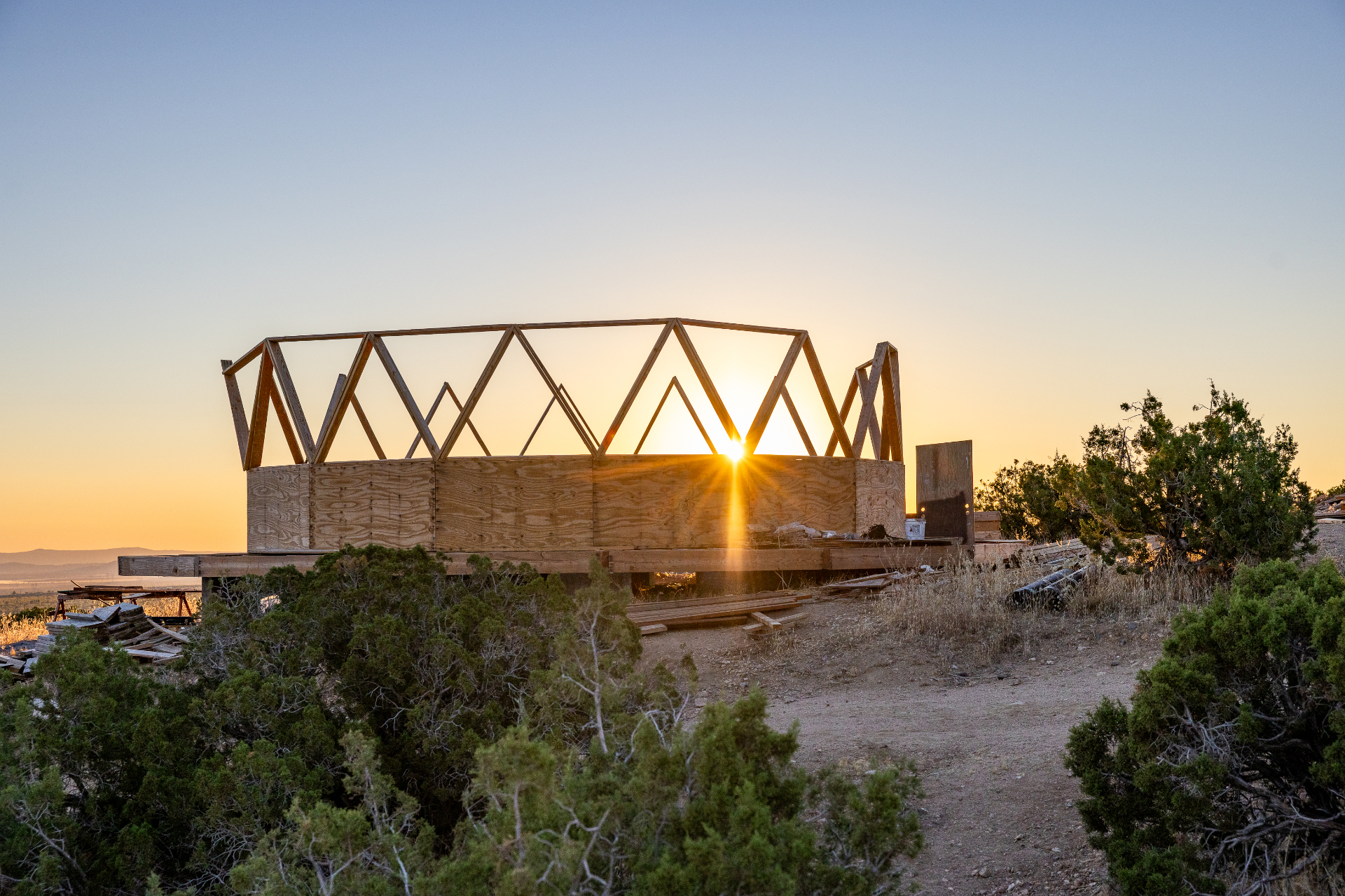 The Dome House frame silhouetted against a bright orange sun on the horizon