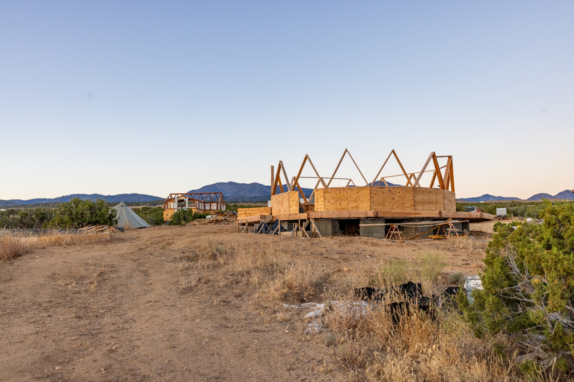Wide view of the desert site with the Dome House frame and greenhouse structure visible in the distance